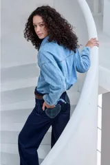 Pantalón de jean azul oscuro, de corte recto y tiro alto, con costuras a contratono y detalle de dobladillo vuelto con estampa a cuadros en tonos verdes y azules.