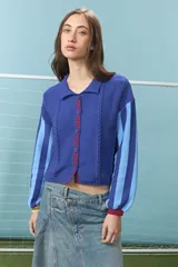 Cardigan de algodón color azul con mangas largas de rayas verticales anchas en tonos azul y celeste, puños en rojo, y bordado en la espalda con diseño de escudo nacional.
