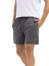 Short de baño de secado rápido, con cintura elástica y cordón ajustable. La parte superior es de color verde agua con un estampado de motivos circulares en tono azul oscuro. La parte inferior es de color terracota con un patrón de microperforaciones.