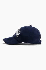 Gorra de pana azul marino de algodón, con bordado frontal en color blanco y cierre ajustable con hebilla metálica en la parte posterior.
