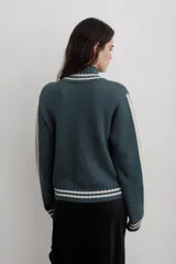 Campera tejida de algodón en color rojo, con cierre frontal completo, cuello alto y puños acanalados con detalles de rayas blancas. Presenta un diseño gráfico con texto blanco en el frente.