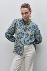Camisa de calce amplio confeccionada en viscosa liviana y fluida, con estampado floral en tonos verde militar y azul. Presenta cuello mao, abertura frontal con botones y mangas largas con puños abotonados.