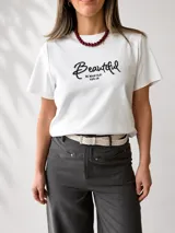 Remera azul marino de manga corta y corte clásico, con estampa bordada con la palabra "Beautiful" en el frente. Incluye un pañuelo de cuello con estampado a cuadros en tonos oscuros.