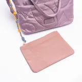Cartera tipo bolso de mano en color rosa, confeccionada en material sintético acolchado con diseño de costuras curvas. Cuenta con doble asa superior, bolsillo frontal con cierre y un detalle decorativo de cordón trenzado con cuentas naranjas en uno de los laterales.