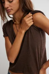Remera de jersey suave color negro, de calce relajado, corte recto y largo corto, con escote en V y mangas cortas caídas con puño fijado.