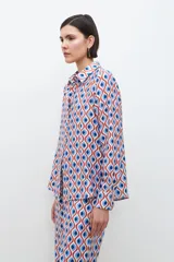 Camisa de manga larga con cuello clásico y estampa geométrica retro en tonos azul, rojo y blanco.