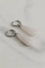 Aros tipo argolla de acero quirúrgico con dije colgante en forma de gota de piedra natural color rosado.