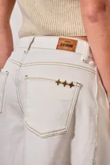Bermuda de denim color blanco con costuras en contraste, tiro medio y ruedo desflecado.
