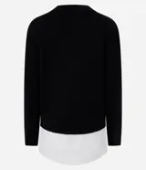 Suéter negro de punto con cuello redondo y mangas largas. Tiene un dobladillo superpuesto de camisa blanca.
