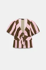 Camisa de rayas verticales rosadas y marrones, con escote en V, mangas corta abullonadas y cierre frontal con múltiples lazadas del mismo tejido. Presenta bajo con acabado de volante.