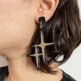 Aros colgantes con base cuadrada negra y dije con forma de estrella negra con interior dorado.