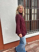 Polera de tejido de punto con diseño de ochos, color bordó, de corte oversize y cuello alto, con puños y ruedo acanalados.