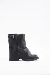 Botas de caña media confeccionadas en cuero vegano color negro, con diseño de solapa frontal y detalle de hebilla metálica en la parte superior.