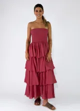 Vestido largo sin tirantes, color rojo, con cuerpo ajustado de nido de abeja y falda larga con múltiples volantes escalonados con bordes deshilachados.