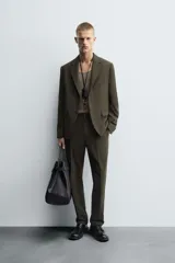 Blazer de corte slim fit en color verde oscuro, con cuello de solapas de muesca, cierre frontal de un botón, bolsillos laterales con solapa y bolsillo de vivo en el pecho.