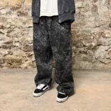Pantalón de corte super baggy con estampado camuflado en tonos grises y negros, confeccionado en denim con efecto lavado.