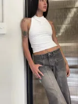 Pantalón de jean gris con efecto lavado, de corte recto y tiro bajo. Presenta costuras verticales decorativas en el frente y bolsillos tipo cargo frontales.
