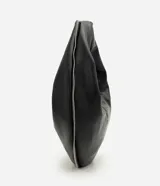 Bolso tipo baguette de formato curvo, confeccionado en poliuretano con acabado que imita el cuero. Presenta una estructura flexible con asa integrada y cierre superior metálico aparente que recorre el contorno.