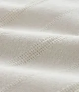 Bermuda recta de playa en color blanco roto, confeccionada en algodón texturizado con efecto de rayas verticales. Posee cintura elástica con cordón ajustable.