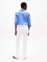 Pantalón jean blanco de corte bootcut y tiro medio, confeccionado en tejido denim elástico de algodón. Cuenta con cierre de cremallera con botón, cinco bolsillos, detalles distintivos de la marca y logo bordado en el bolsillo trasero.