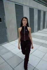 Top estilo nadador con cierre frontal completo, confeccionado en tela con efecto lavado artesanal en tonos rojizos y negros. Presenta un diseño ajustado con costuras visibles y un pequeño logo bordado en el pecho.