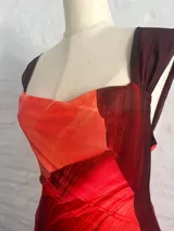 Vestido largo de microtul con estampado abstracto en tonos rojos y naranjas, con escote drapeado y tirantes finos.