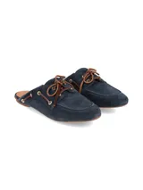 Zueco de gamuza azul marino, de diseño estilo náutico sin talón con cordones de cuero marrón y ojalillos metálicos dorados.