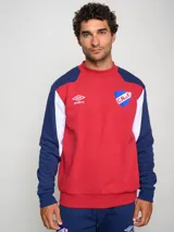 Buzo de felpa con diseño de bloques de color, predominantemente rojo en el cuerpo y azul marino en las mangas y hombros. Presenta el escudo del Club Nacional de Football y el logo de Umbro en el pecho.