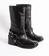 Bota de cuero negra con caña media, punta cuadrada, taco bloque y arnés con hebillas y tachas plateadas.