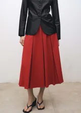 Falda midi de tiro medio con diseño evasé y tablas anchas. Cuenta con forro interior y cierre oculto.