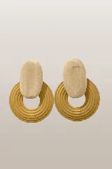 Caravanas de diseño geométrico compuestas por una pieza superior ovalada de madera clara y una pieza inferior circular de color mostaza con textura de anillos concéntricos.