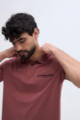 Remera polo Brooksfield de manga corta color bordó, con bolsillo en el pecho, cierre frontal con botones y detalles a contraste en tono oscuro en cuello, puños y ribete del bolsillo.