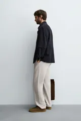 Pantalón de corte recto confeccionado en tejido de sarga con estructura diagonal. Presenta cintura elástica, bolsillos delanteros, bolsillos traseros de vivo y cierre frontal con cremallera y botón.