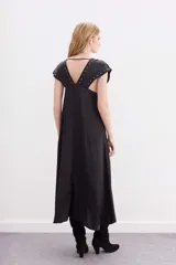 Vestido largo de viscosa jacquard, color negro, con escote en V y mangas cortas. Presenta detalles de ojalillos metálicos decorativos en el escote y en los bordes de las mangas.