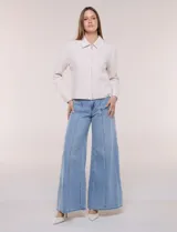Camperita corta blanca de punto elastizado, con cuello camisero, cierre frontal completo y mangas largas con puños anchos abotonados.