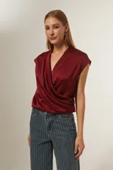 Blusa de satén color bordó, con diseño cruzado tipo sobre, cuello en V y mangas cortas integradas.