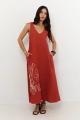 Vestido largo de corte holgado en color azul, con escote en V, breteles regulables y bolsillos laterales. Presenta un delicado diseño de flores bordadas en el lateral inferior.