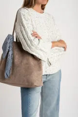 Sweater de punto con textura de ochos, color gris melange con motas oscuras, cuello redondo y mangas largas con terminación acampanada.