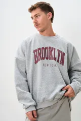Buzo gris con estampa en el frente con el texto "Brooklyn New York" en color bordó.