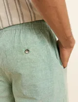 Bermuda de lino color beige, de corte recto y holgado, con cintura elastizada y cordón ajustable.