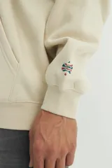 Canguro azul con capucha forrada, cordones de algodón y ojalillos metálicos. Tiene un calce oversize y un pequeño logo estampado en el pecho.