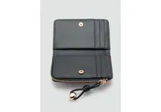 Billetera pequeña de diseño rectangular en acabado charol negro. Cuenta con cierre perimetral con tirador decorativo y detalle de logo metálico en el frente.