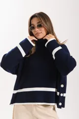 Sweater azul marino de punto con cuello alto, mangas largas con puños blancos y detalle de botones en el lateral.