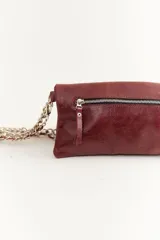 Bandolera de cuero negra con diseño en zigzag de tachas plateadas y asa de cadena metálica.