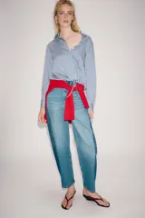 Camisa de cuello solapa y manga larga, con bajo ajustable mediante cordones y cierre frontal con botones ocultos. Diseño a rayas blancas y azules.