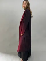 Tapado de paño de lana con diseño de solapas amplias, corte recto y bolsillos laterales ocultos. Presenta un degradado de color que va desde un tono bordó intenso en las solapas y puños hacia un tono más oscuro en el cuerpo.