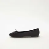 Bailarinas de mujer en color negro, confeccionadas en material tipo antelina con acabado suave. Presentan un diseño clásico de punta redondeada y un pequeño lazo decorativo en la parte frontal.