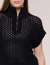 Buzo de punto color blanco de algodón calado, con cuello alto acanalado, medio cierre metálico dorado y mangas cortas estilo japonesa con puños anchos acanalados.