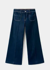 Pantalón wide leg de denim azul oscuro, de tiro alto con trabillas y cierre frontal de cremallera y botón. Presenta bolsillos de parche delanteros.