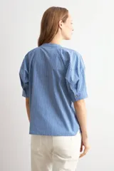 Camisa de manga corta a rayas azules y blancas, con cuello mao y cierre frontal oculto.